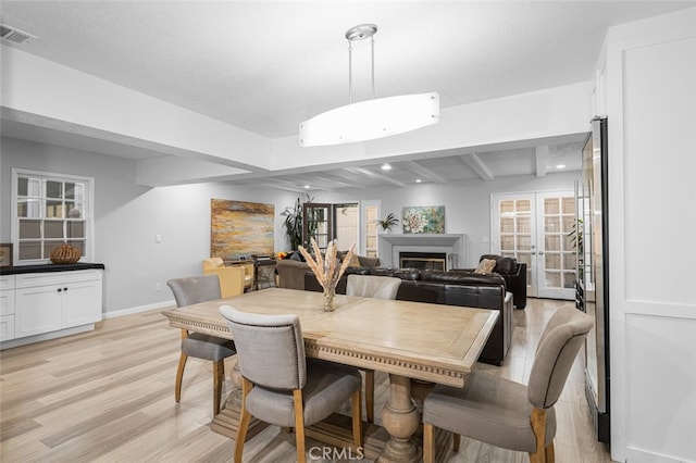 dining space with french doors, beamed ceiling, and light hardwood / wood-style floors