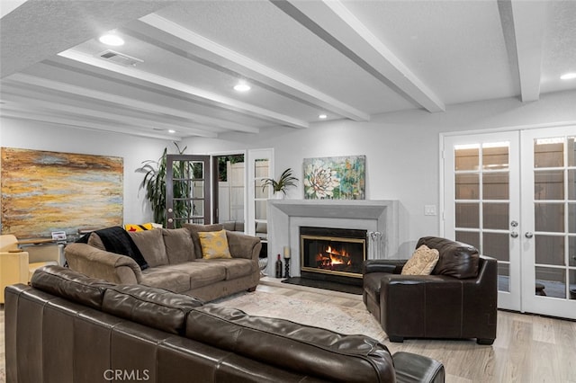 living room with light hardwood / wood-style floors, beamed ceiling, and french doors