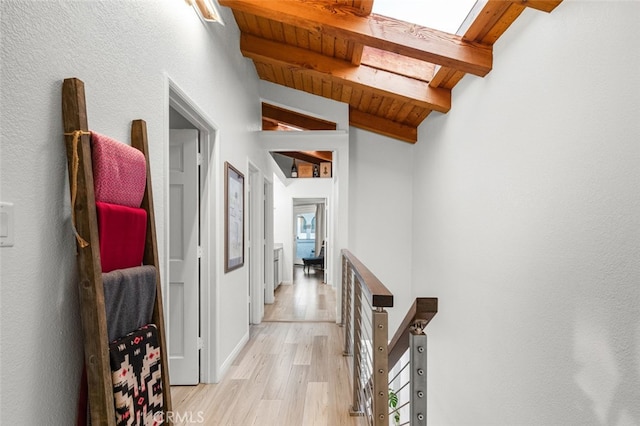 hallway with wooden ceiling, light hardwood / wood-style flooring, and vaulted ceiling with skylight