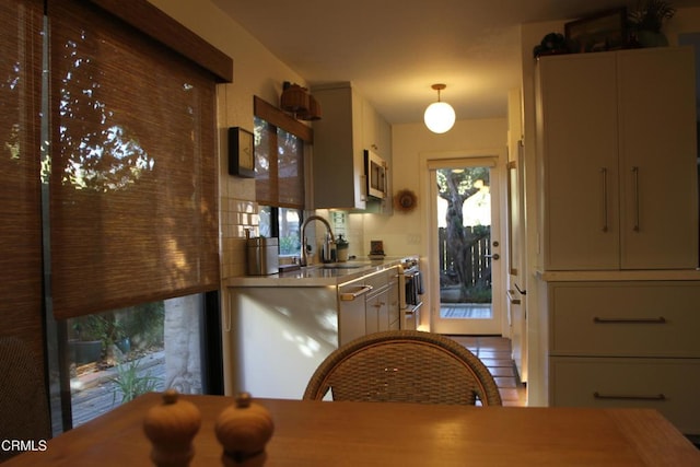 kitchen with appliances with stainless steel finishes, decorative light fixtures, and sink