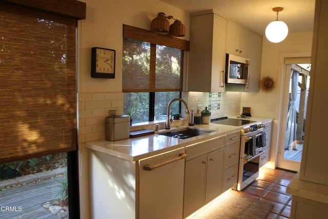 kitchen featuring stainless steel appliances, backsplash, decorative light fixtures, white cabinets, and sink