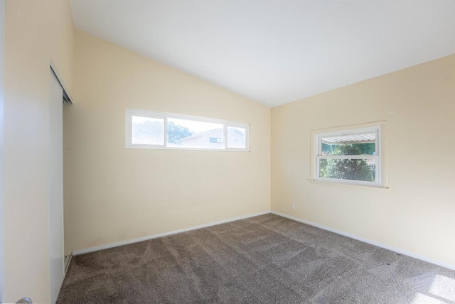 carpeted spare room with vaulted ceiling