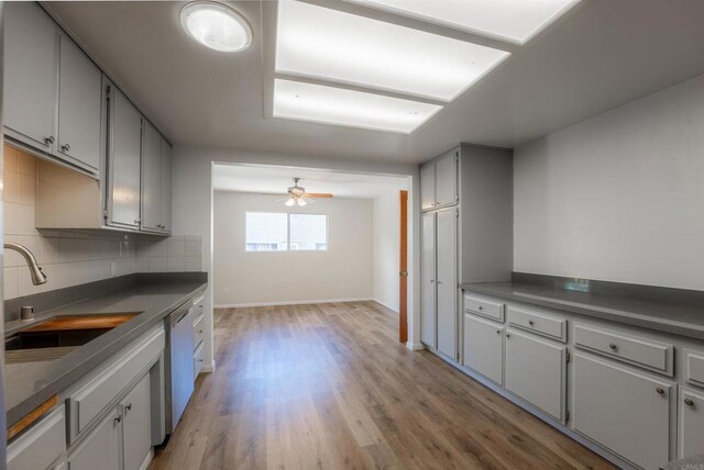 kitchen with light hardwood / wood-style floors, ceiling fan, tasteful backsplash, stainless steel dishwasher, and sink