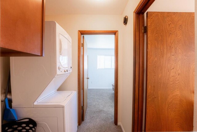 washroom with stacked washer / drying machine and carpet flooring