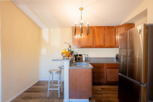 kitchen featuring pendant lighting, sink, a kitchen breakfast bar, stainless steel fridge, and a chandelier