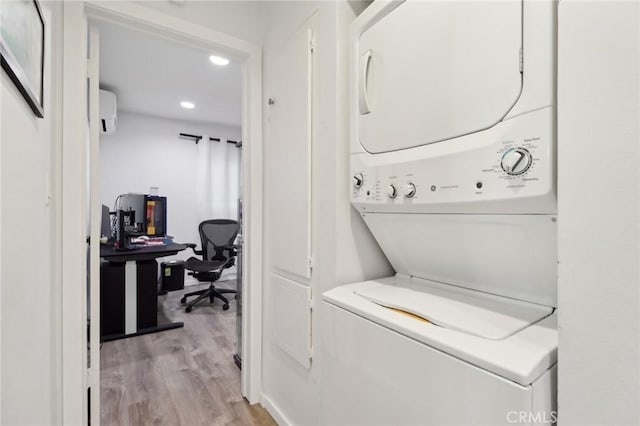 clothes washing area with stacked washer and dryer, a wall unit AC, and light hardwood / wood-style flooring