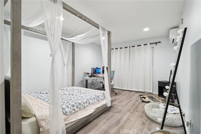 bedroom featuring hardwood / wood-style flooring and an AC wall unit