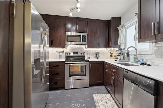 kitchen with decorative backsplash, sink, dark tile patterned flooring, and appliances with stainless steel finishes