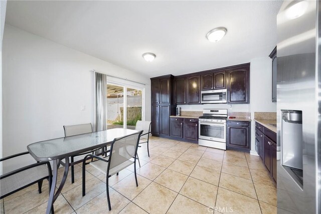 kitchen with light tile patterned flooring, stainless steel appliances, and dark brown cabinets