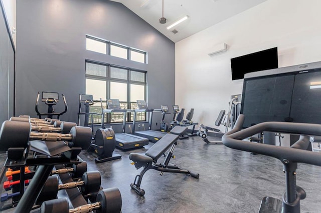 workout area with ceiling fan, a towering ceiling, and a wall unit AC