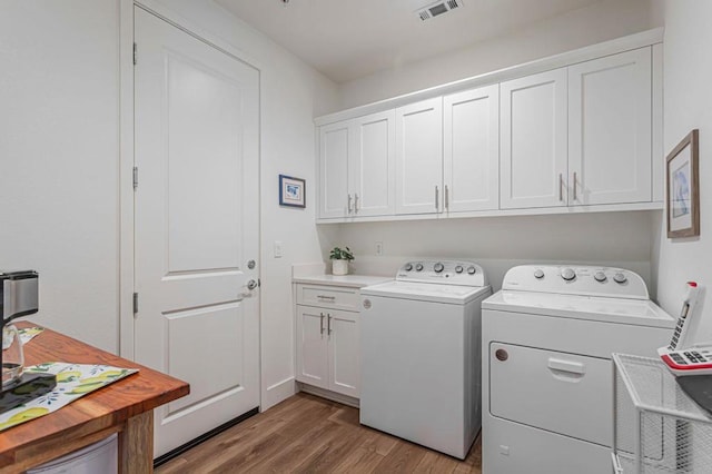 laundry area with light hardwood / wood-style flooring, cabinets, and washing machine and clothes dryer