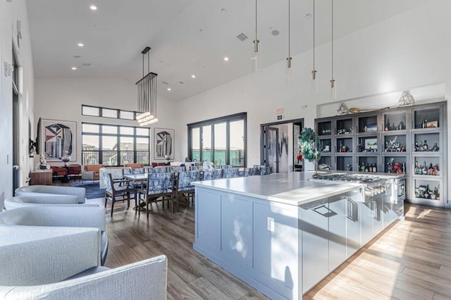 kitchen with plenty of natural light, high vaulted ceiling, hanging light fixtures, and light wood-type flooring