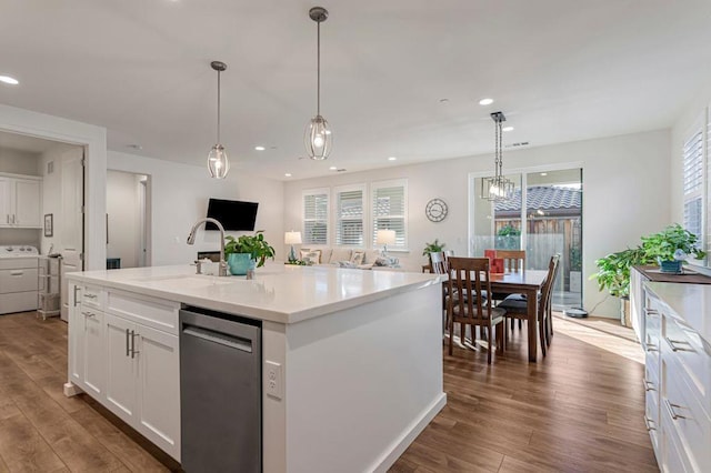 kitchen featuring washer / clothes dryer, decorative light fixtures, a center island with sink, and white cabinets