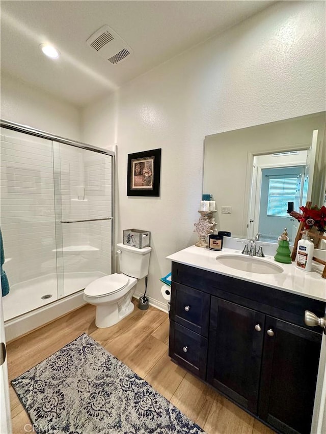 bathroom featuring a shower with shower door, hardwood / wood-style floors, toilet, and vanity