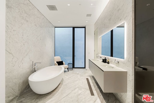 bathroom with a wall of windows, vanity, a healthy amount of sunlight, and a bath