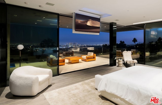 bedroom with hardwood / wood-style flooring, a wall of windows, and golf simulator