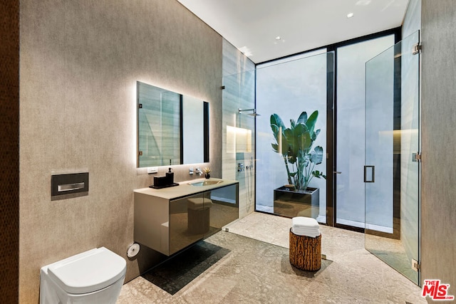 bathroom featuring a shower with door, a wall of windows, vanity, and toilet