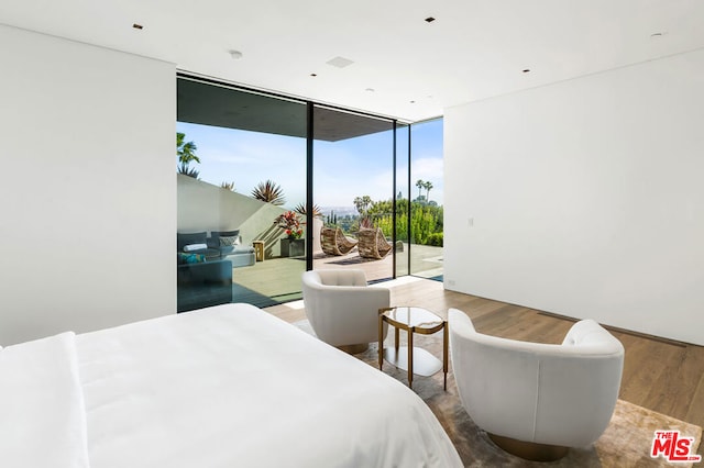 bedroom with a wall of windows, hardwood / wood-style floors, and access to outside