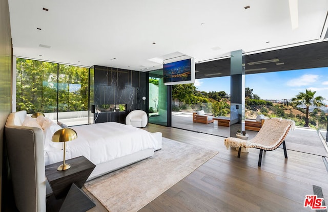 bedroom with access to outside, wood-type flooring, and floor to ceiling windows