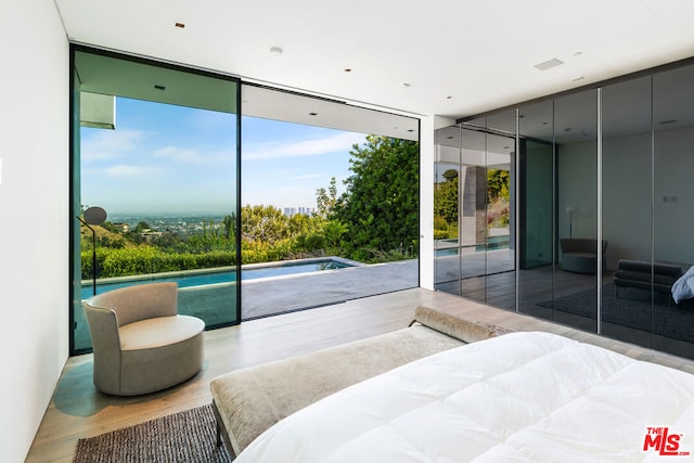 bedroom featuring hardwood / wood-style floors, access to outside, and multiple windows