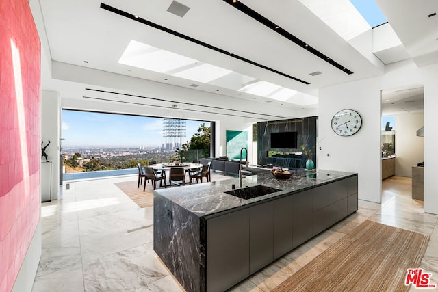 kitchen with a large island with sink, sink, and dark stone countertops