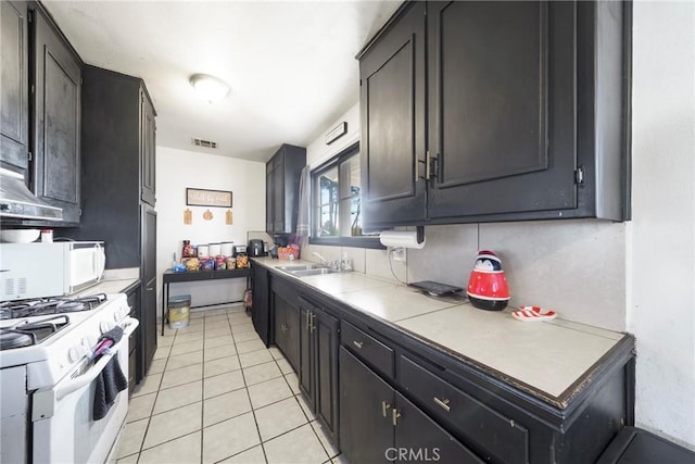 kitchen with sink, white appliances, light tile patterned floors, and tile counters