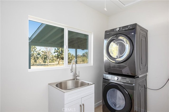 washroom featuring cabinets, sink, and stacked washing maching and dryer