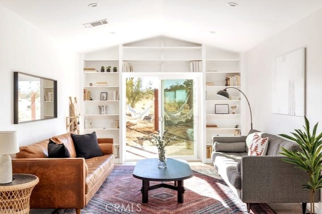 living area with built in shelves and vaulted ceiling