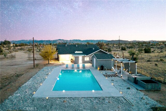 pool at dusk featuring a mountain view and an outbuilding