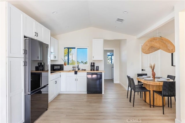 kitchen with lofted ceiling, pendant lighting, black appliances, light hardwood / wood-style floors, and white cabinetry