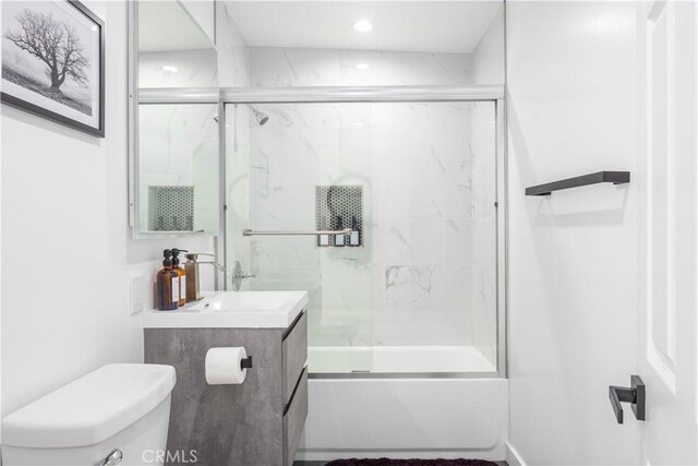 full bathroom featuring toilet, bath / shower combo with glass door, and vanity