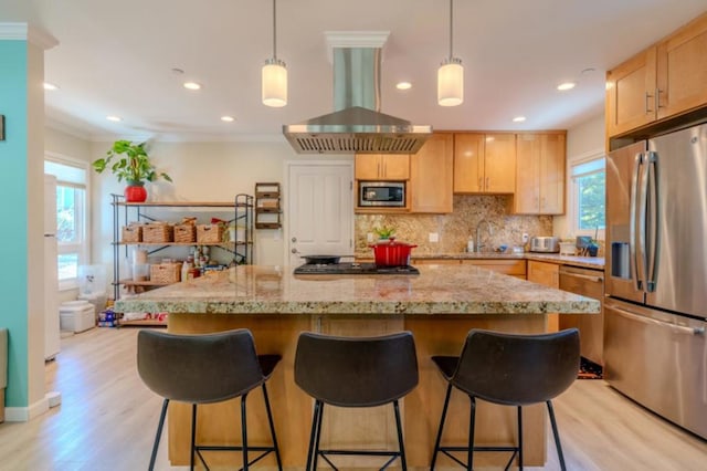 kitchen with appliances with stainless steel finishes, extractor fan, light brown cabinets, and a center island