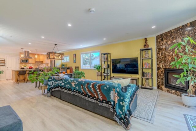 living room with a fireplace, ornamental molding, and light hardwood / wood-style flooring