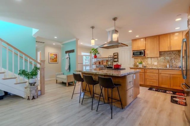 kitchen with decorative light fixtures, a center island, light hardwood / wood-style flooring, appliances with stainless steel finishes, and island range hood