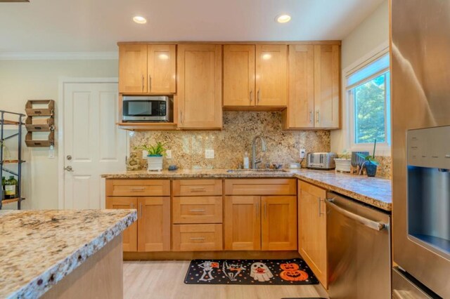 kitchen featuring stainless steel appliances, light brown cabinetry, light stone counters, and sink