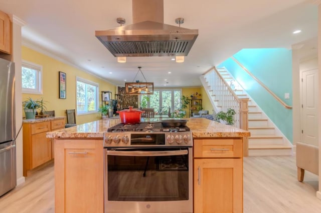 kitchen featuring appliances with stainless steel finishes, a kitchen island, light brown cabinetry, light wood-type flooring, and range hood