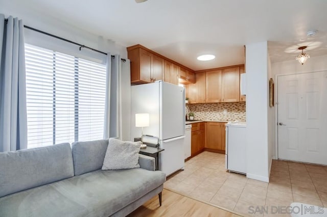 kitchen featuring tasteful backsplash, washer / dryer, white appliances, light brown cabinets, and light tile patterned floors