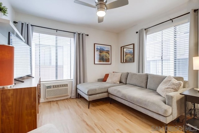 living room with light hardwood / wood-style floors, a wealth of natural light, a wall unit AC, and ceiling fan