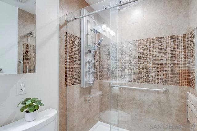 bathroom featuring toilet and a shower with shower door