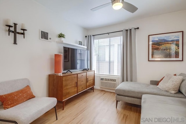 living area with ceiling fan, a wall mounted AC, and light wood-type flooring