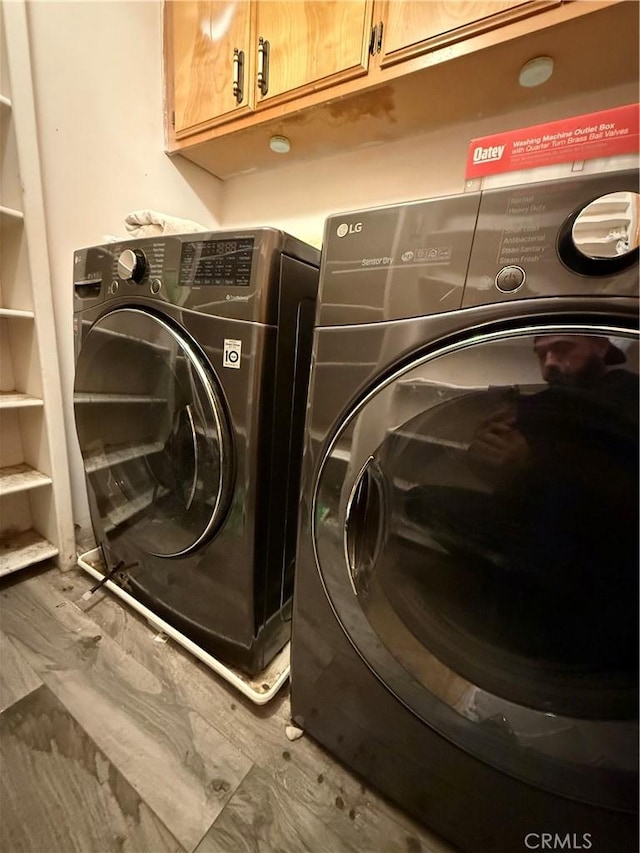 washroom with washer and dryer and cabinets