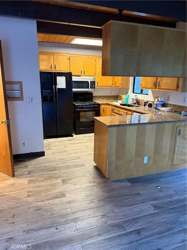 kitchen with sink, black appliances, kitchen peninsula, and light wood-type flooring