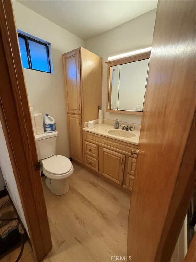 bathroom featuring toilet, hardwood / wood-style flooring, and vanity