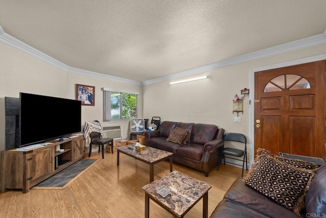 living room with a wall mounted AC, a textured ceiling, ornamental molding, and hardwood / wood-style floors