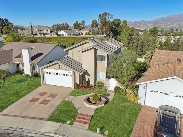 view of front of house featuring a mountain view, a garage, and a front lawn