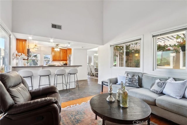 living room with ceiling fan, a towering ceiling, and tile patterned floors