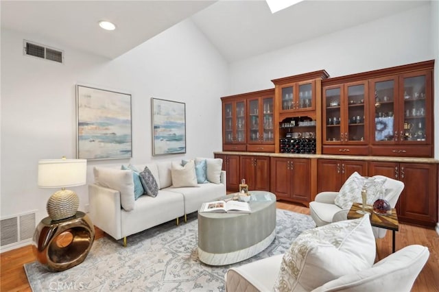 interior space featuring vaulted ceiling with skylight and light hardwood / wood-style flooring