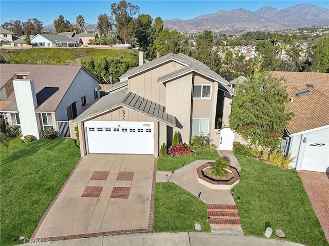 view of front of home with a garage, a mountain view, and a front lawn