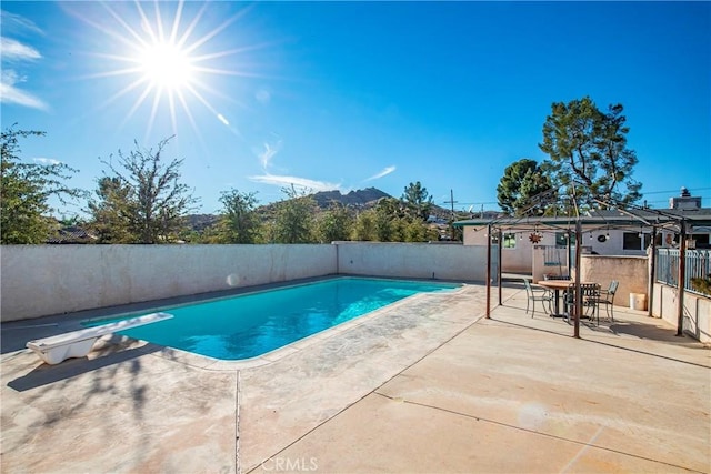 view of swimming pool featuring a diving board and a patio