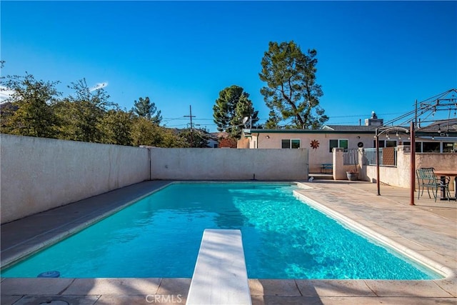 view of swimming pool featuring a diving board and a patio area